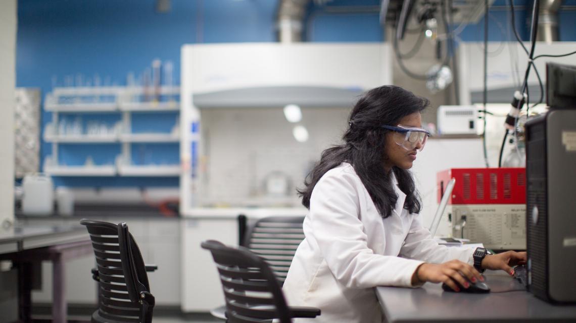 Researcher wearing googles working at a computer in a research laboratory